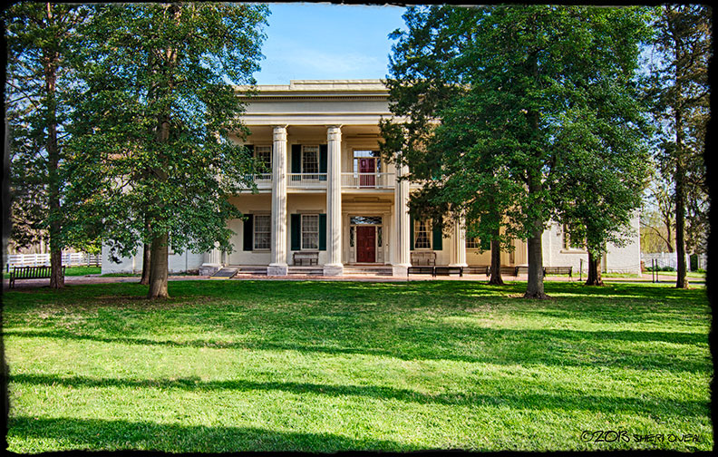 A large white house with columns in the middle of a grassy field at the Hermitage