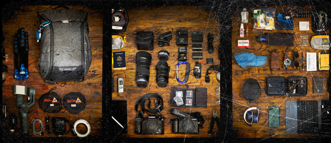 A pro's photography gear and products are laid out on a wooden table.