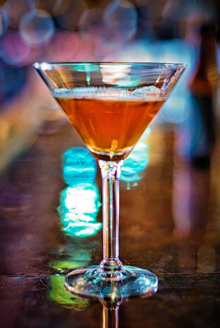 a specialty martini drink sitting on a bar at a restaurant