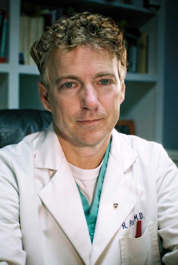 Rand Paul sitting in his office wearing a white laboratory coat