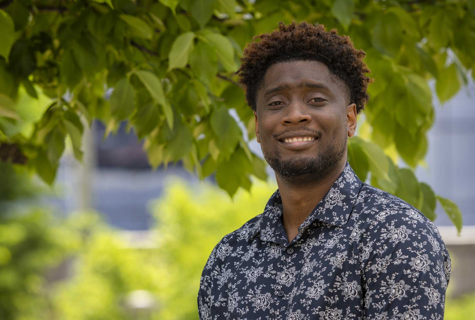 outdoor headshot with green leaves in the background of Brice Perez
