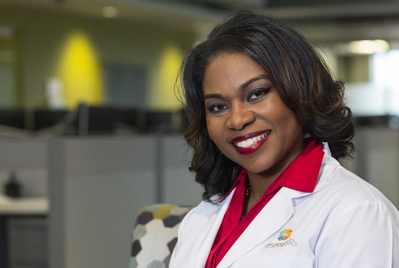 executive portrait of Lametra Scott in a white lab coat and red shirt in front of cubicles