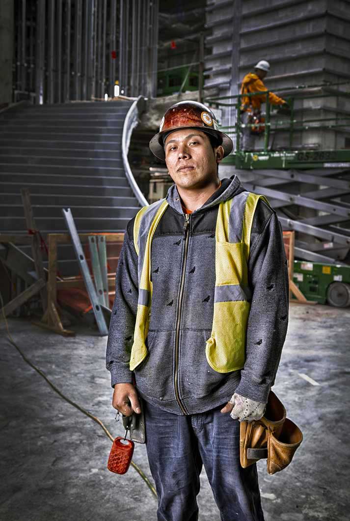 portrait of a construction worker wearing a hard hat, yellow vest, and gray jacket holding his keys