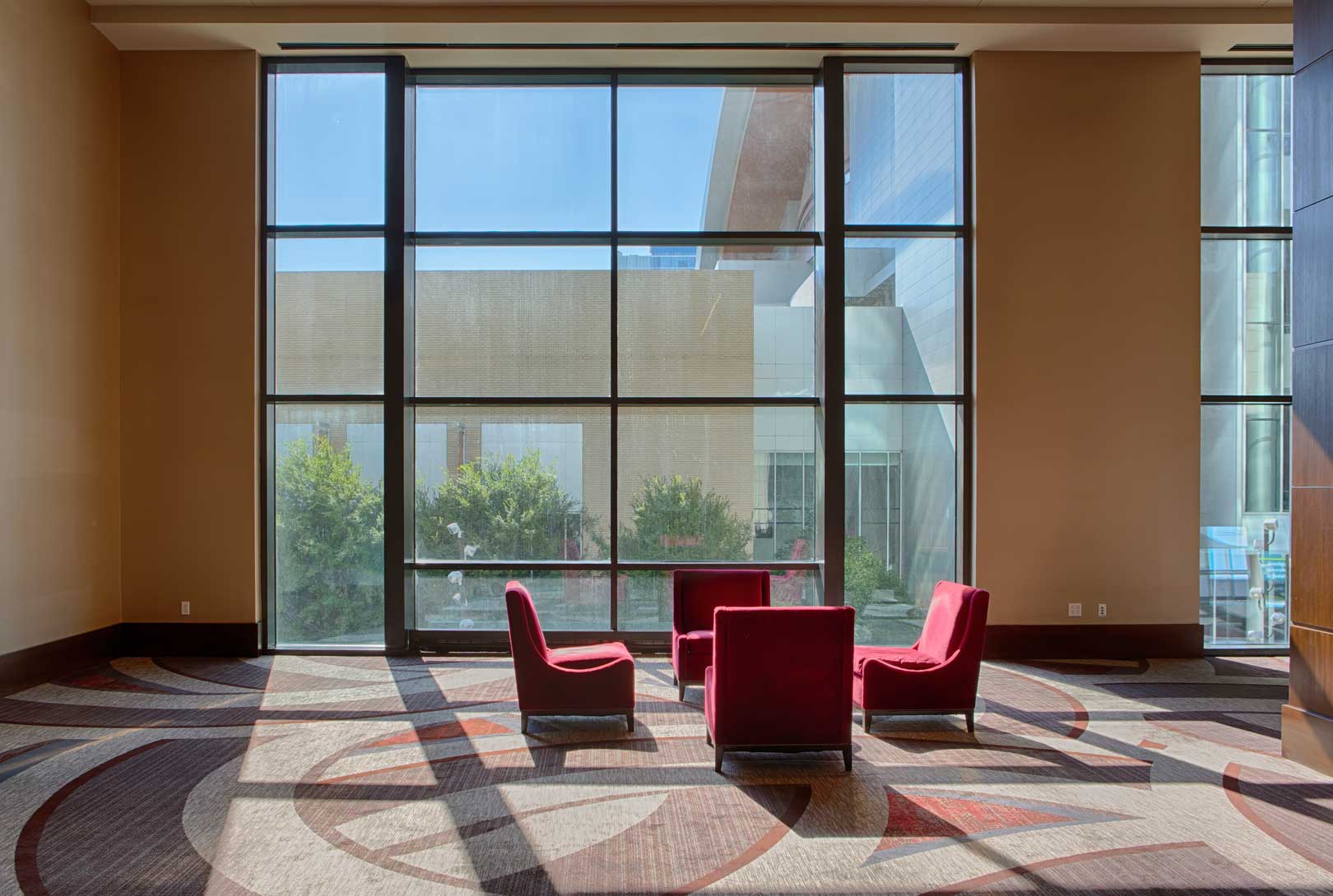 red chairs upstairs Convention Sitting Area At The Omni Hotel near windows with tan and red design carpet