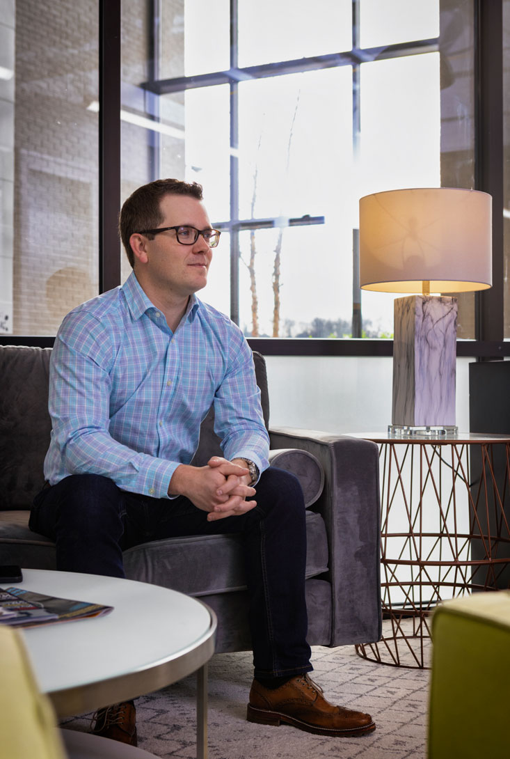 executive photo of Rob Bellenfant sitting in waiting area near a window and lamp