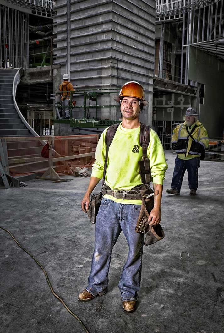 construction worker wearing safety goggles tool belt suspenders at a construction site