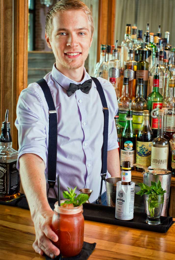 Graham "Guice" Fuze in suspenders and bow tie behind bar with speciality drink