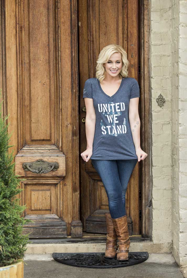 A woman standing in front of a door wearing a t - shirt that says united stand.