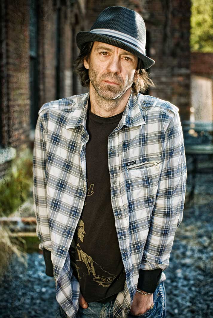Nashville Songwriter Travis Meadows with black hat white striped button up brown t-shirt near brick building