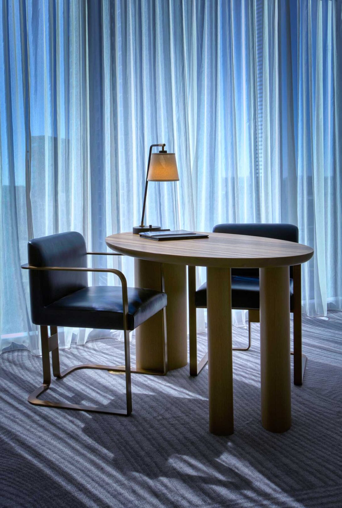 A desk, lamp, and chair in a room.