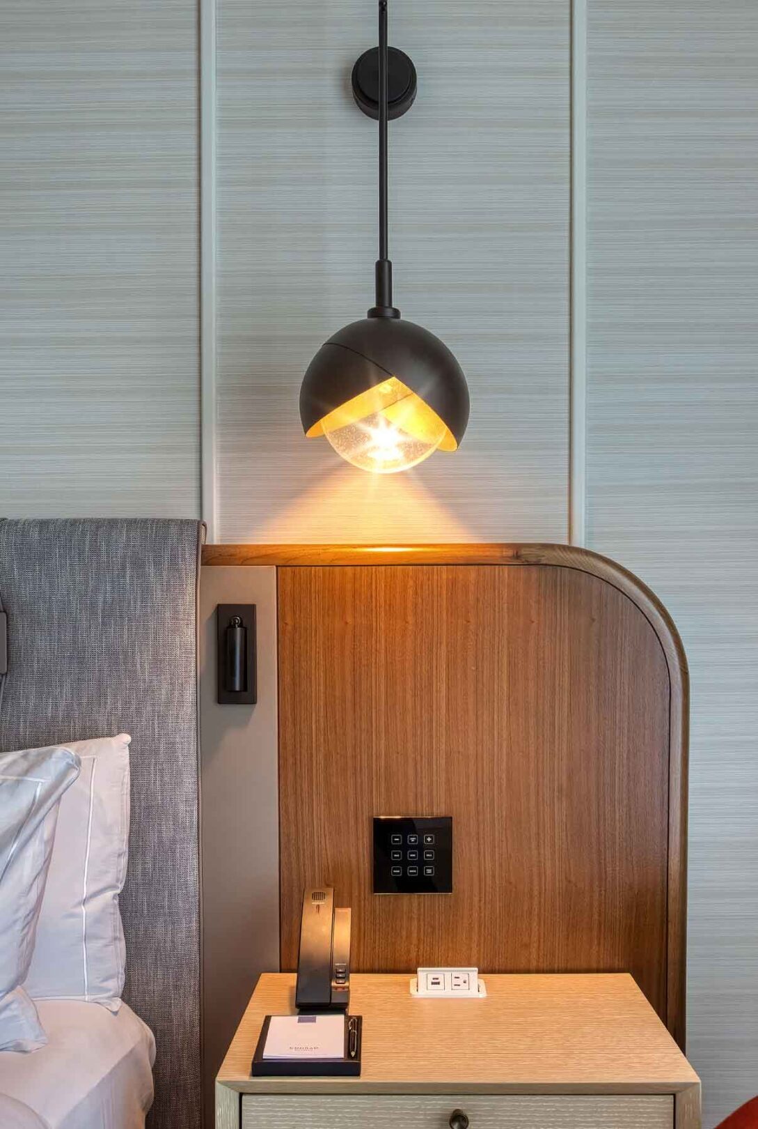 A bed in a hotel room with a bedside lamp.