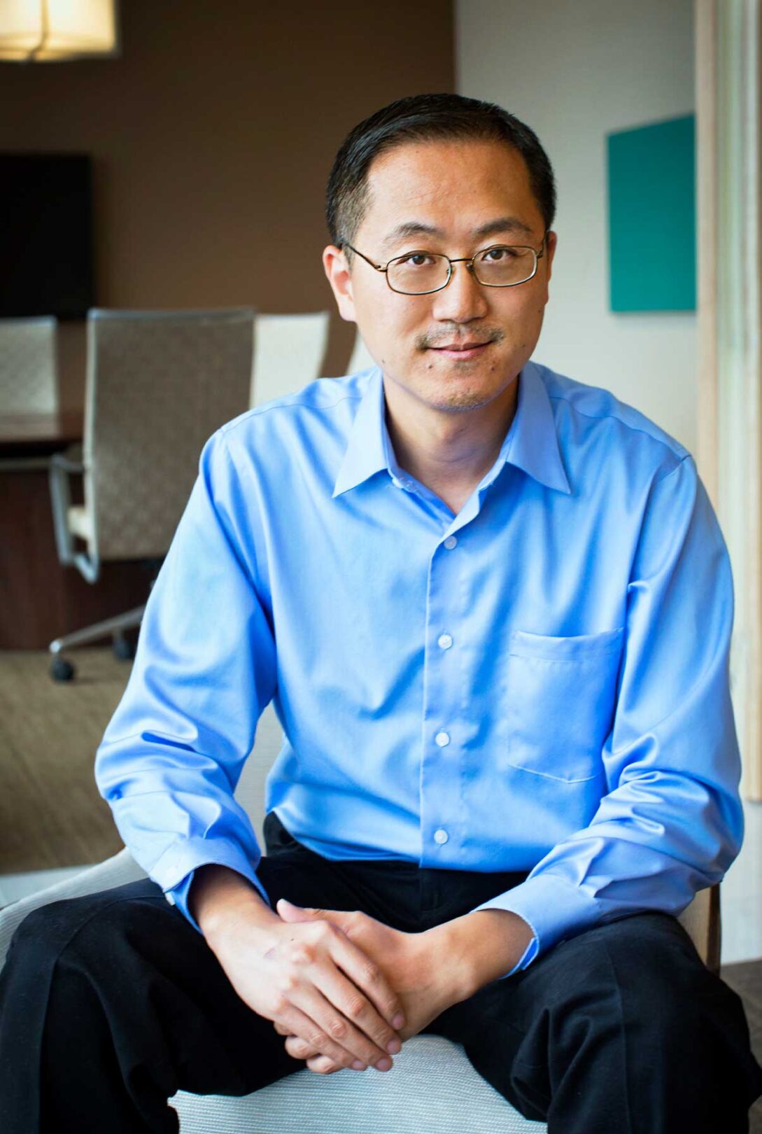 A man in a blue shirt sitting on a chair.