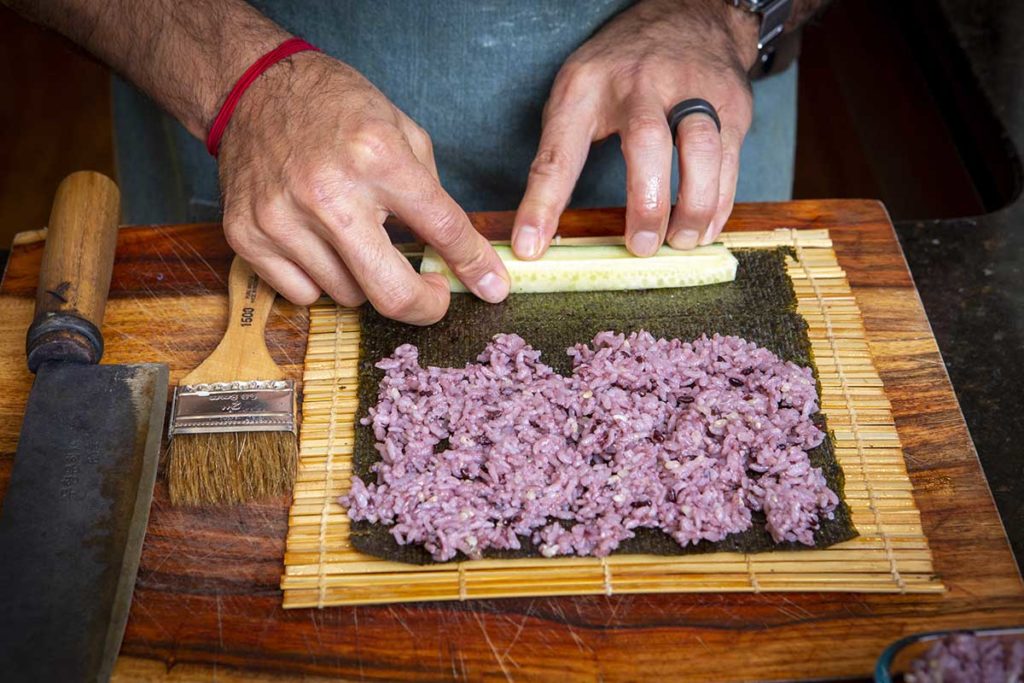 adding cucumber to a seaweed roll