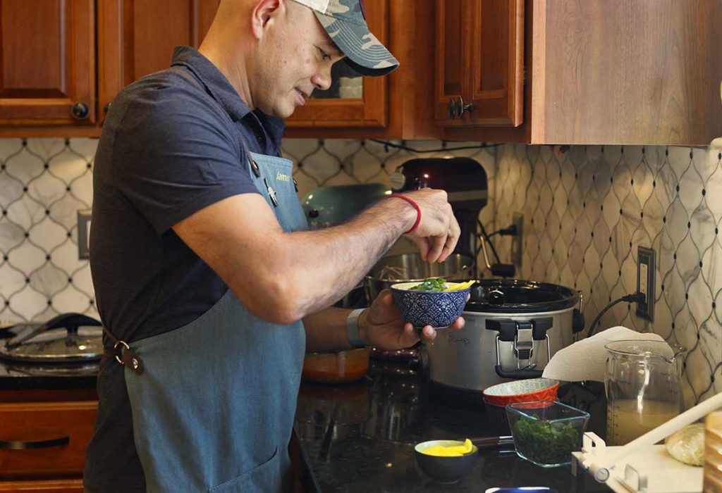 man adding green unions to tteokbokki with cheese sauce
